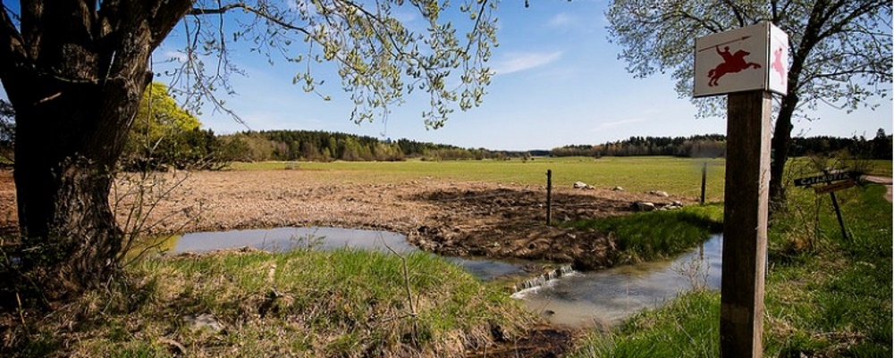 Skylt för tidens väg med Igelbäcken i bakgrunden